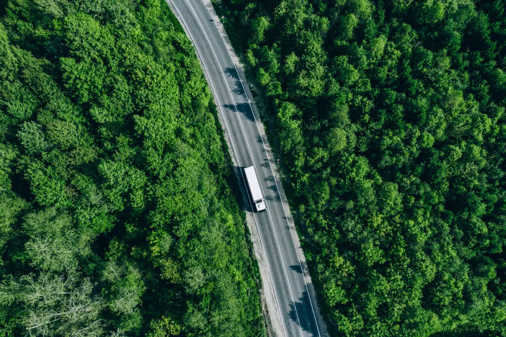 Kamion na cesti kroz zeleno područje kao prikaz održivog transporta i lanca opskrbe