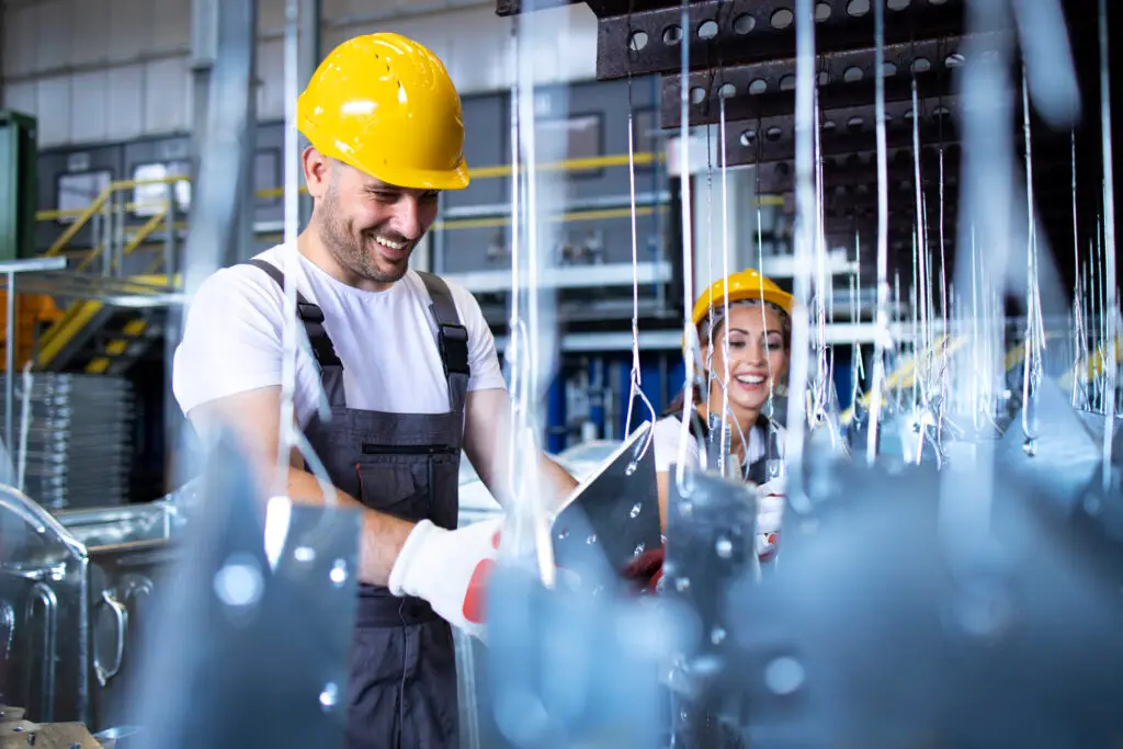 Radnici u zaštitnim kacigama rade u industrijskom pogonu, što simbolizira proizvodnju, industrijske inovacije i tehnološki razvoj.