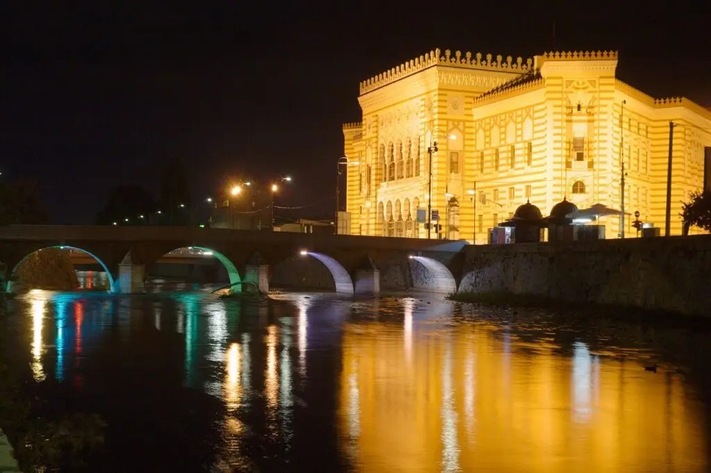 Sarajevska Vijećnica osvijetljena noću uz rijeku Miljacku u Sarajevu, Bosna i Hercegovina.
